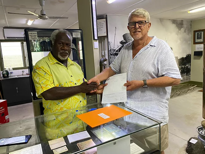 Two men shaking hands over a check, possibly a Reserve Bank funding transaction.