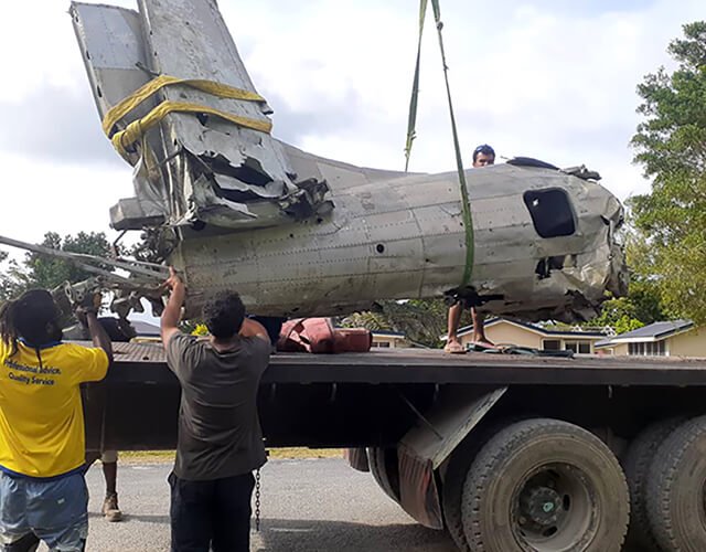 Crane lifts Dauntless wreck for museum display, showing damage and recovery crew.