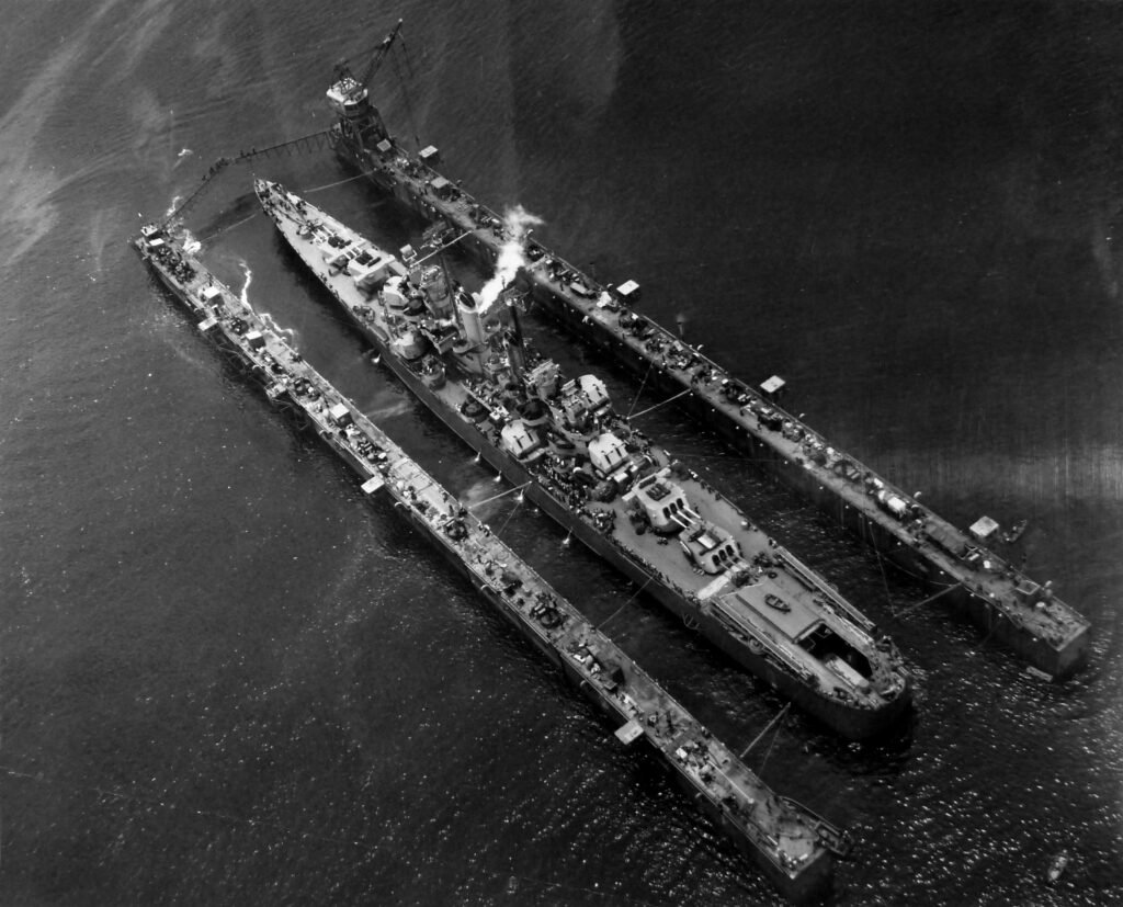 Floating dry dock lifting a large naval ship from the water