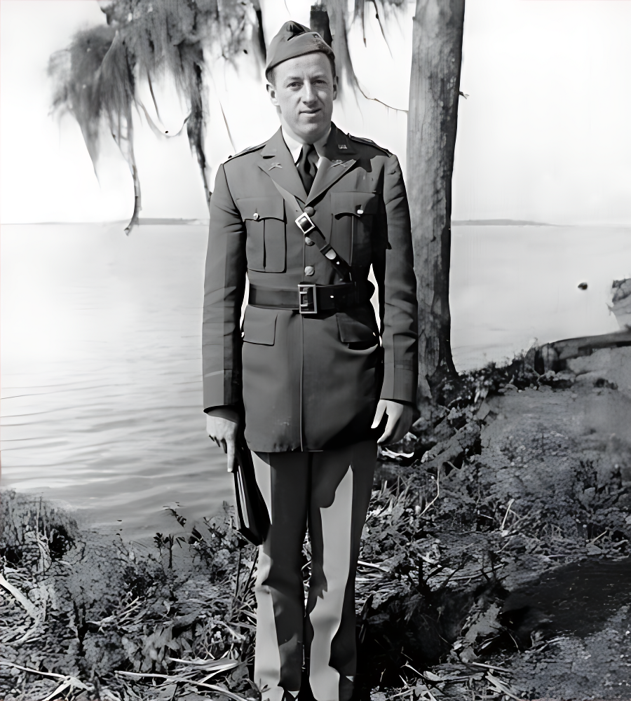 Man in military uniform stands outdoors near water