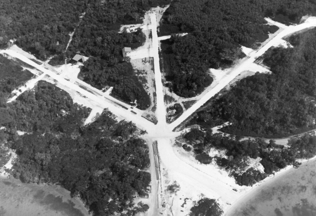 Aerial view of a jungle airfield with multiple runways and buildings.