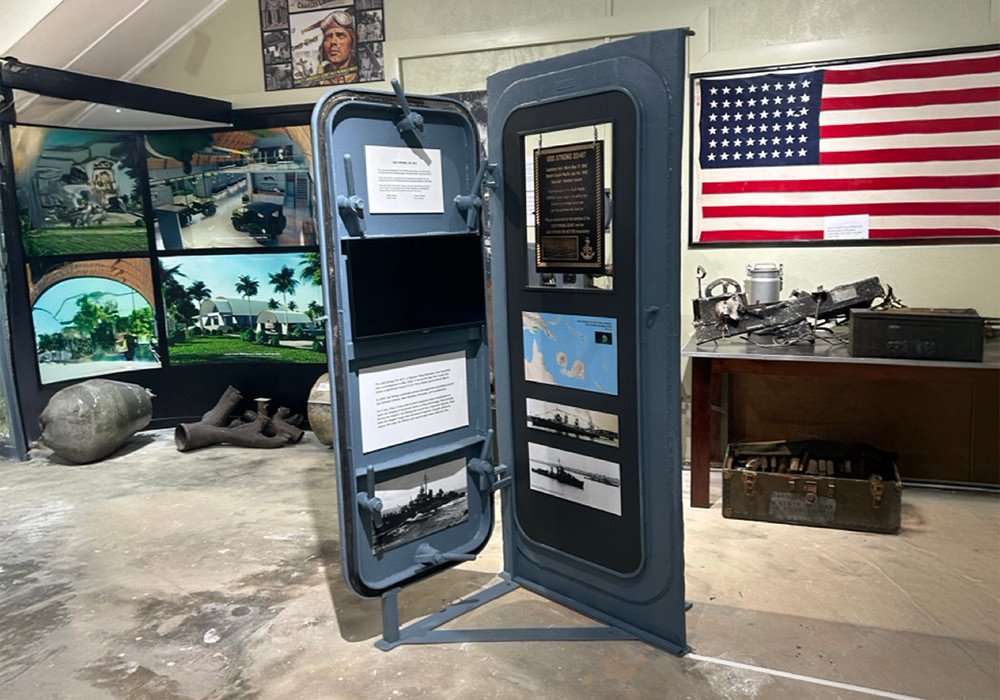 Naval display with a ship's door, American flag, and historical photos