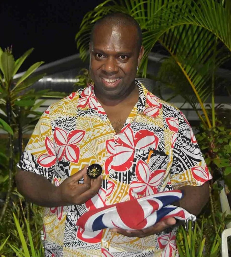 Man in a floral shirt holding a medal and folded flag