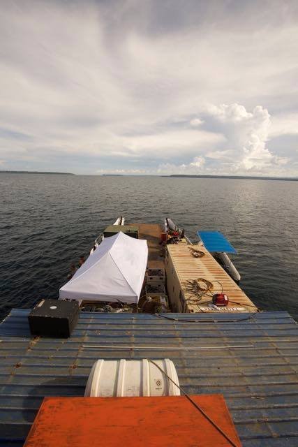 Elwood J Euart barge with cargo, including a tent and shipping container, on water.