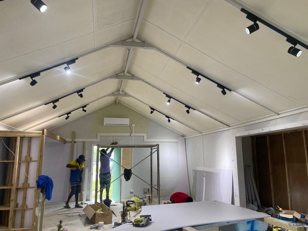 Construction workers installing track lighting in a new building location.