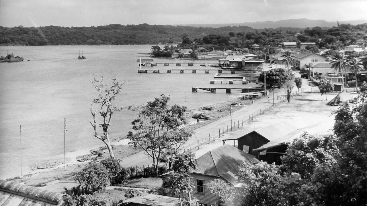 Efate Base: Aerial view of a harbor with docked ships and buildings along the coast.