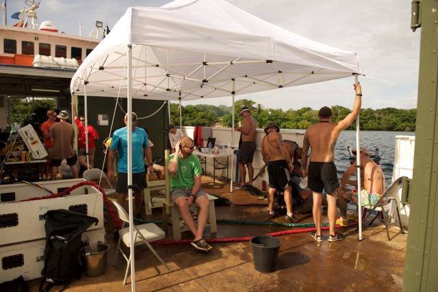 Elwood J Euart crew under a tent on a boat deck.