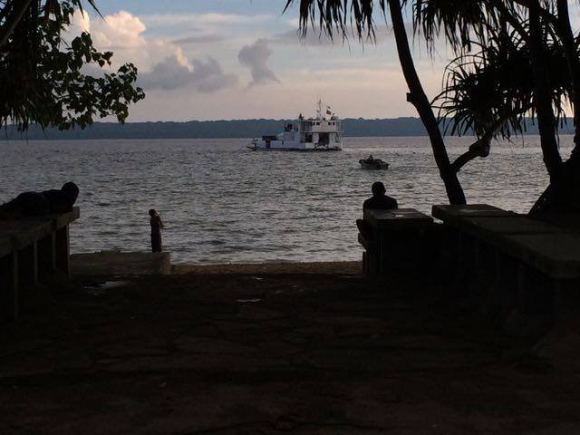 Boat on the water near a beach with people silhouetted