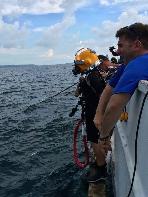 Elwood J Euart diver in yellow helmet prepares to enter the water from a boat.