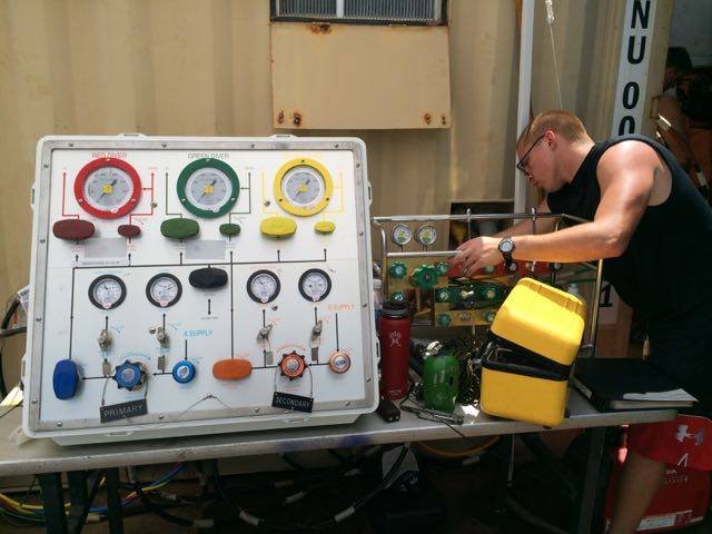 Man checks diving gas panel with gauges and hoses.