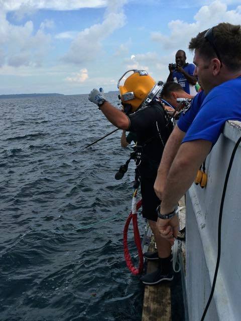 Commercial diver in yellow helmet prepares for dive from boat