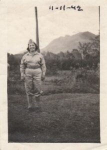 Woman in military uniform, dated 11-11-42, with mountains in background.