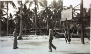 25th Infantry Division soldiers play basketball near tents and palm trees.