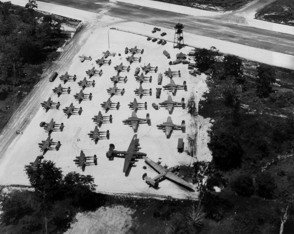 Aerial view of a WWII airfield with numerous P-38 Lightning fighter planes parked.
