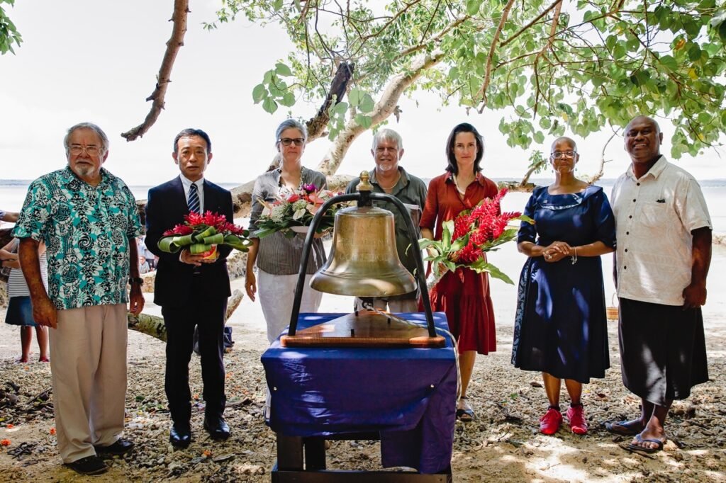 Coolidge Commemoration: Dignitaries pose with a bell on a beach.