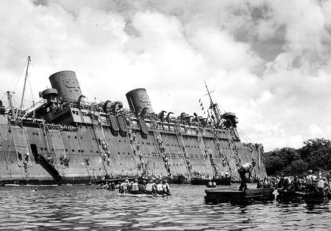 Sinking troopship SS President Coolidge with hundreds of soldiers clinging to its side during WWII.