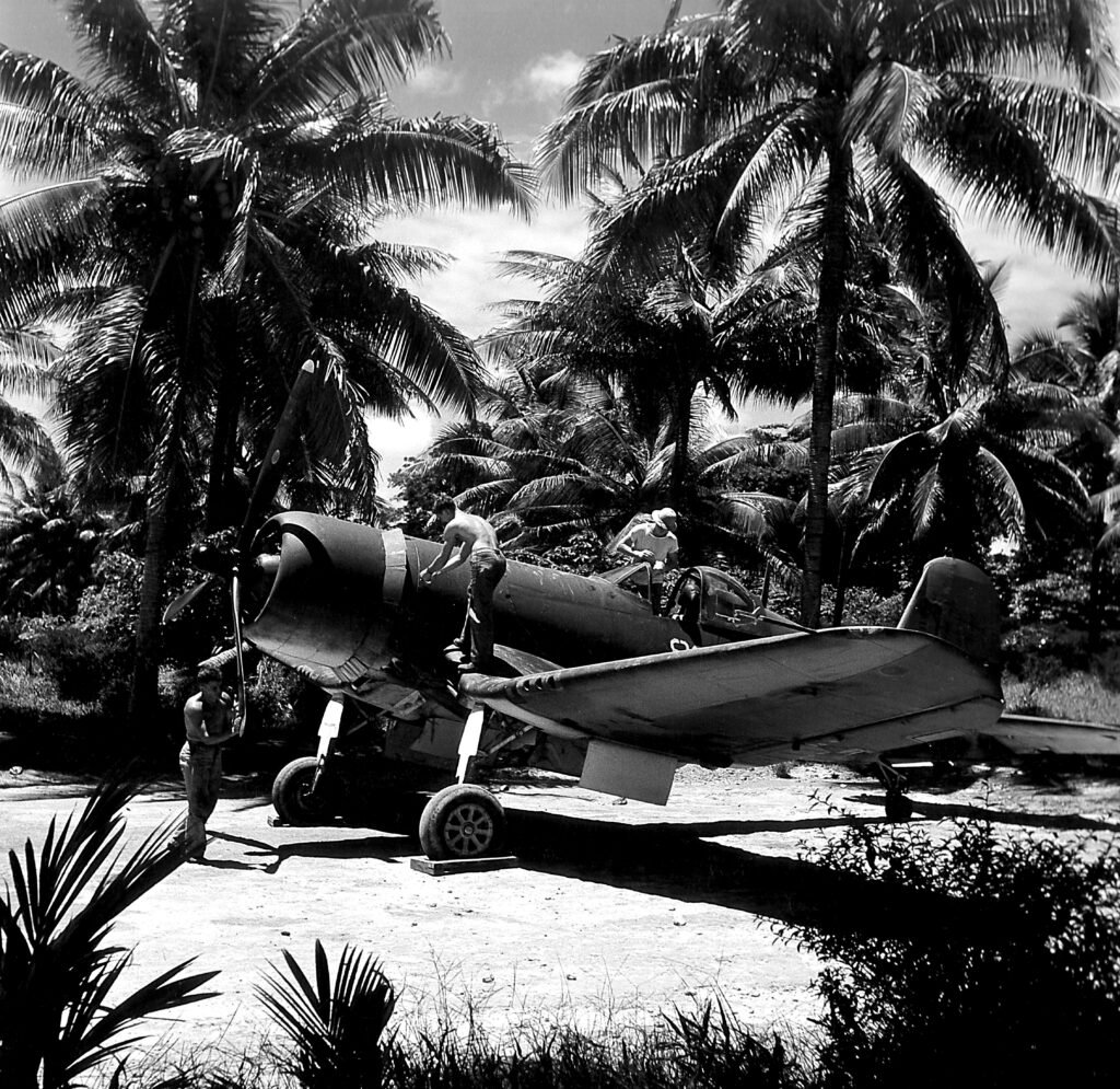 WWII Corsair aircraft on a tropical airfield with crew.