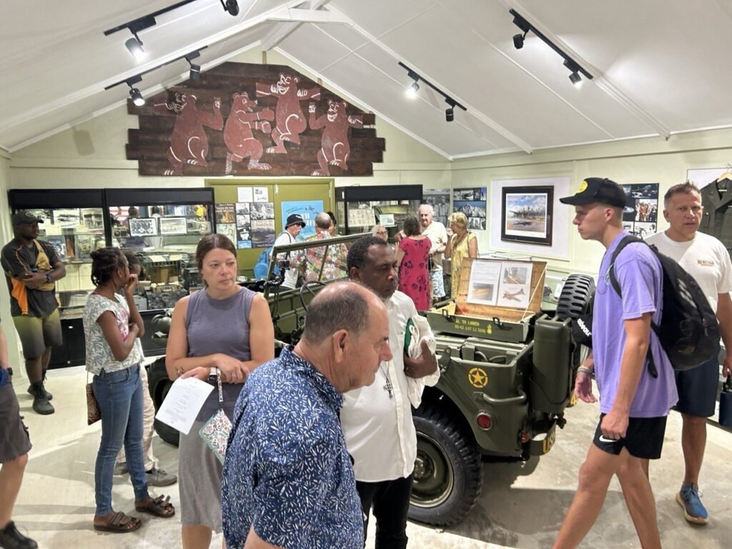 People viewing a vintage military jeep and exhibits in a museum