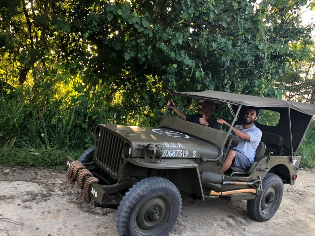 Two men in a vintage olive-drab jeep with USA 20687319 S
