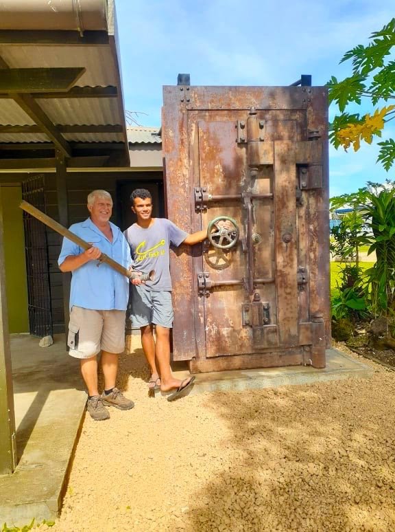 Men with a large, rusted vault door, possibly related to "The Vault" blog.