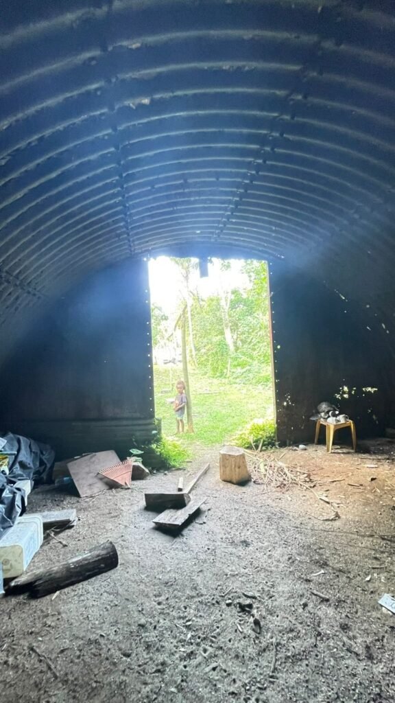 Child peeks out from dark, abandoned bunker entrance to lush green landscape