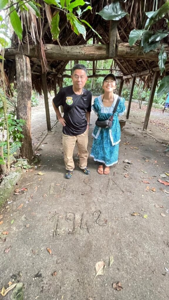 Couple standing near "1942" carved in concrete in a tropical setting