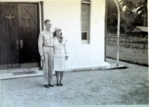 Couple in formal attire standing outside a building, possibly for a 25th-anniversary celebration.