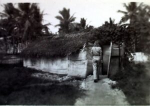 25th Infantry Division soldier walks towards a hut in a tropical setting.