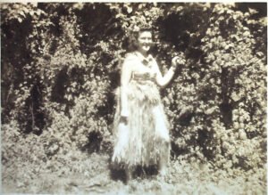 Woman in a grass skirt poses for a photo during a 25th celebration.