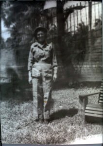 Black and white photo of a woman in military uniform standing in a yard.