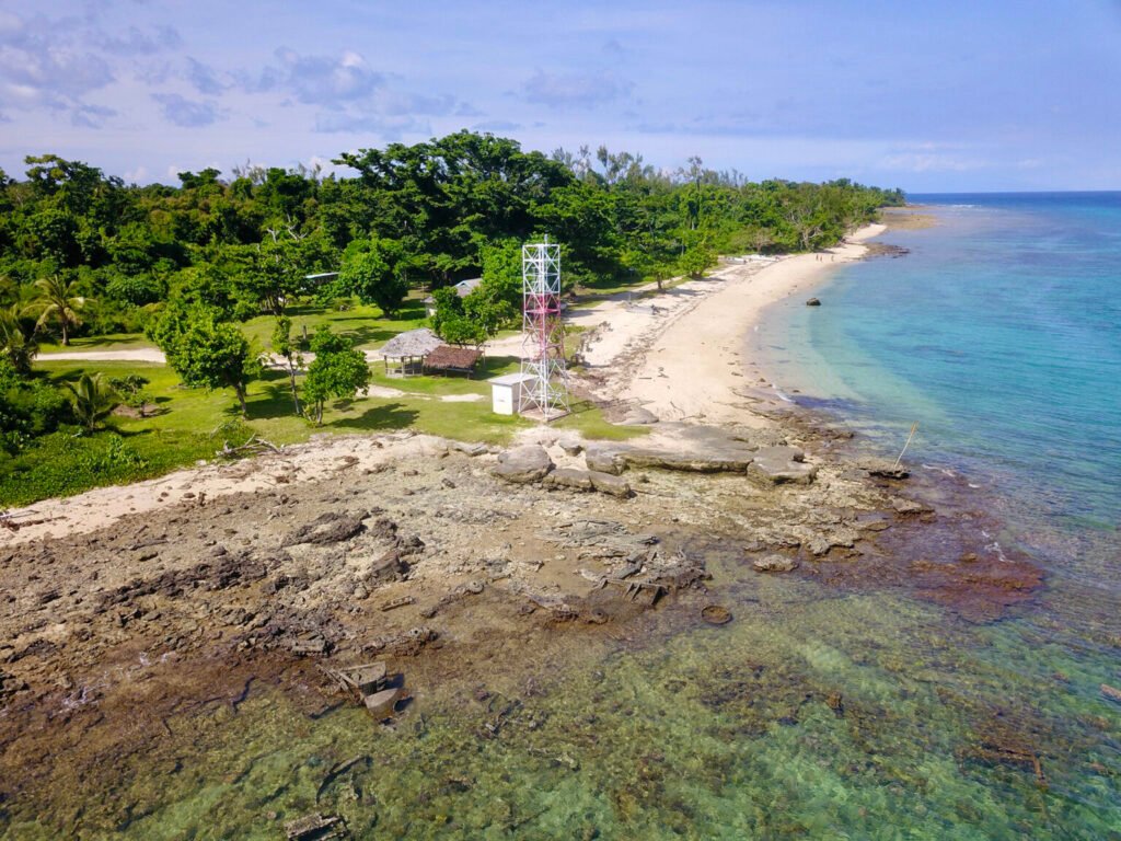 Aerial view of Million Dollar Point, Vanuatu, with a colorful tower on a tropical beach.