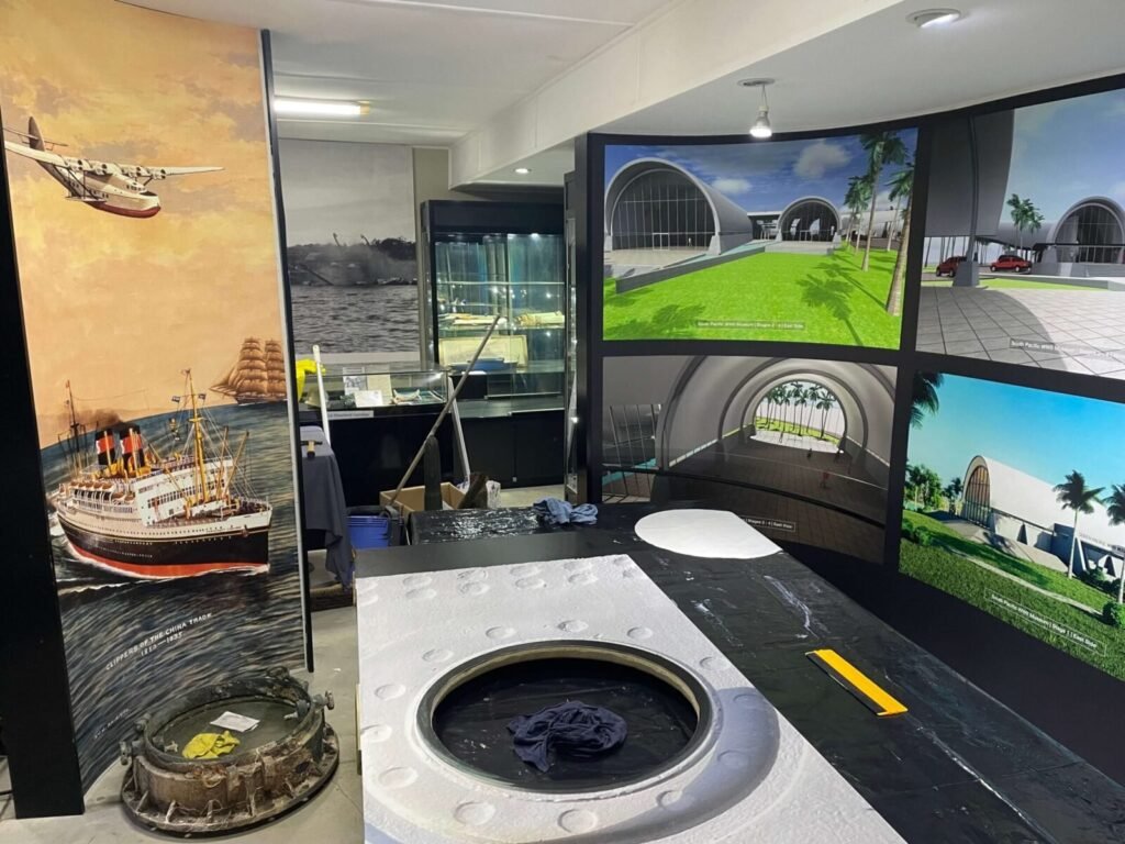 Museum exhibit with ship murals, digital displays of future museum, and a model ship.
