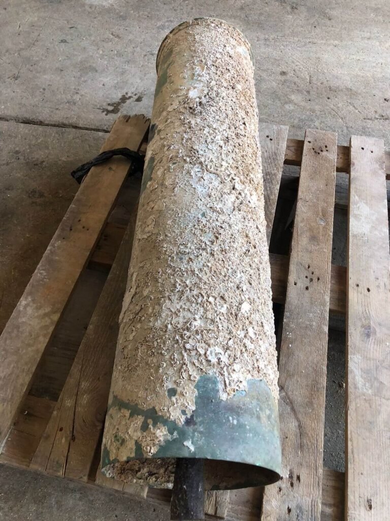 Large, encrusted pipe on wooden pallets