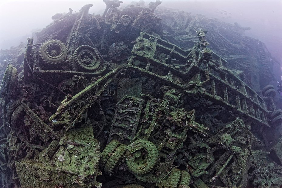 Underwater shipwreck of military vehicles, covered in marine growth