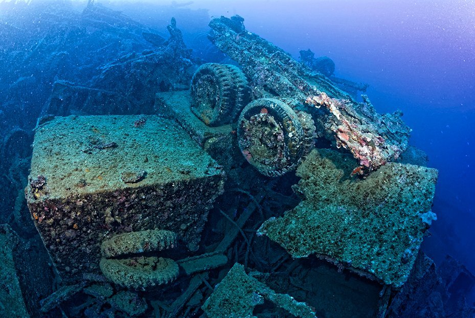 Sunken WWII truck and artillery on the seabed, a historical artifact.