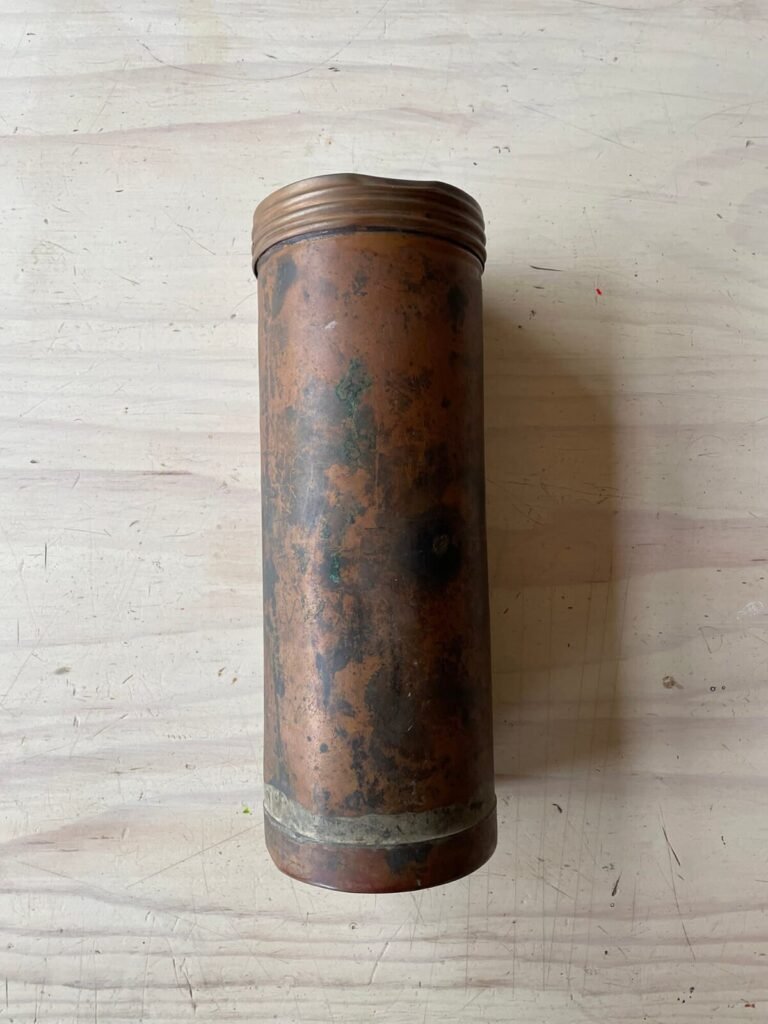 Antique copper canister with a textured lid, showing signs of age and patina.