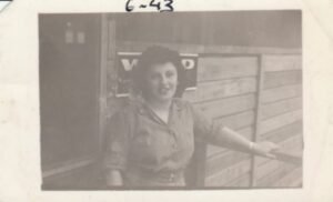 Woman in uniform, 6-43, outside building with V sign
