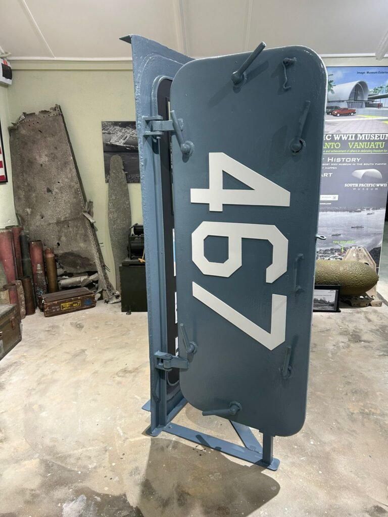 WWII museum display: large gray watertight door numbered 467